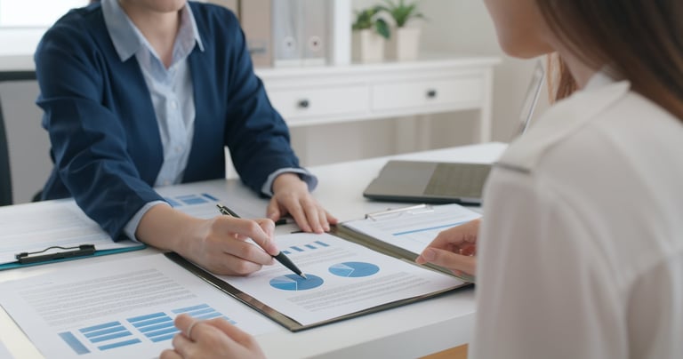 Asia stock trader agent or Sale tax loan broker advice brief and point hand to graph report talk to client at office desk show budget chart data or legal result on claim form