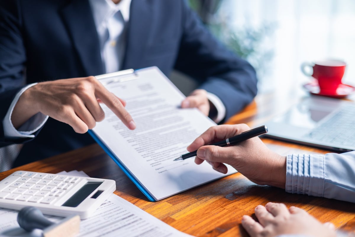 Businesswoman reviewed mortgage document and contract with their client, ensuring loan and credit details were clear, while discussing estate insurance and other finance aspects.