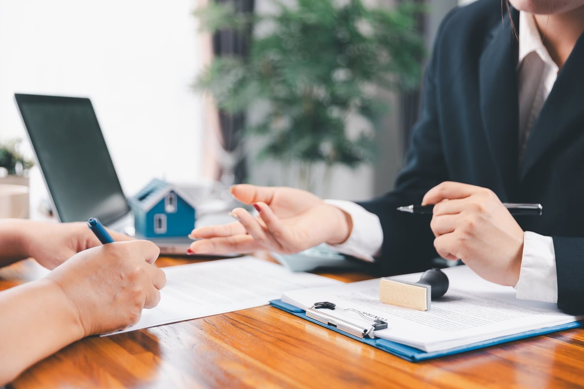 Bank approve loan to buy home concept. Real estate agent talked about terms of home purchase agreement, asked customer to sign documents to make contract legally. approved mortgage application form.