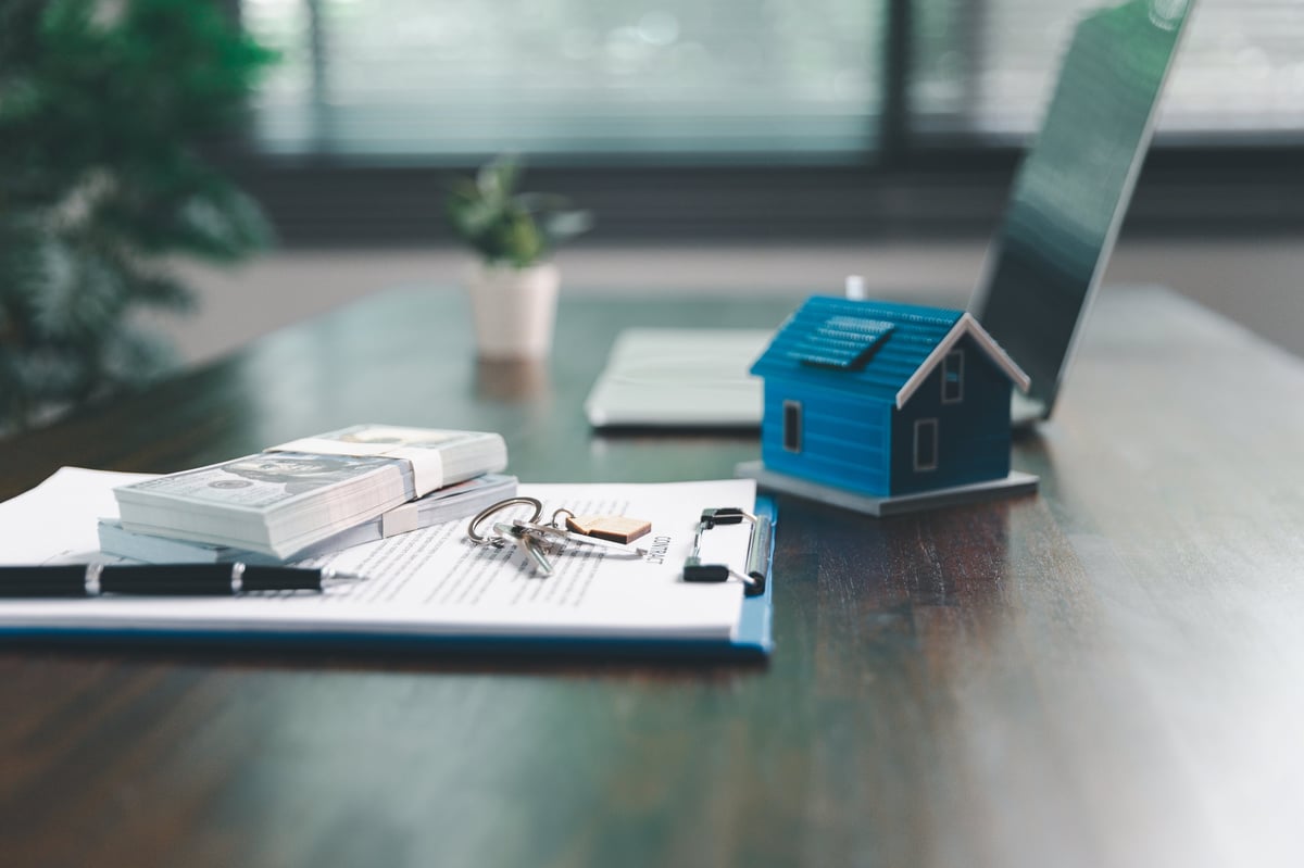 House model placed on table alongside coins, paperwork symbolizes real estate investment, property valuation, representing financial planning, mortgage options, market analysis in property business.