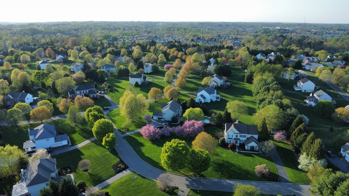 Aerial view of a residential community in spring with rows of suburban homes and tree-lined streets