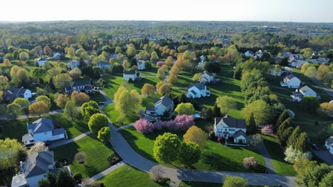 Aerial view of a residential community in spring with rows of suburban homes and tree-lined streets
