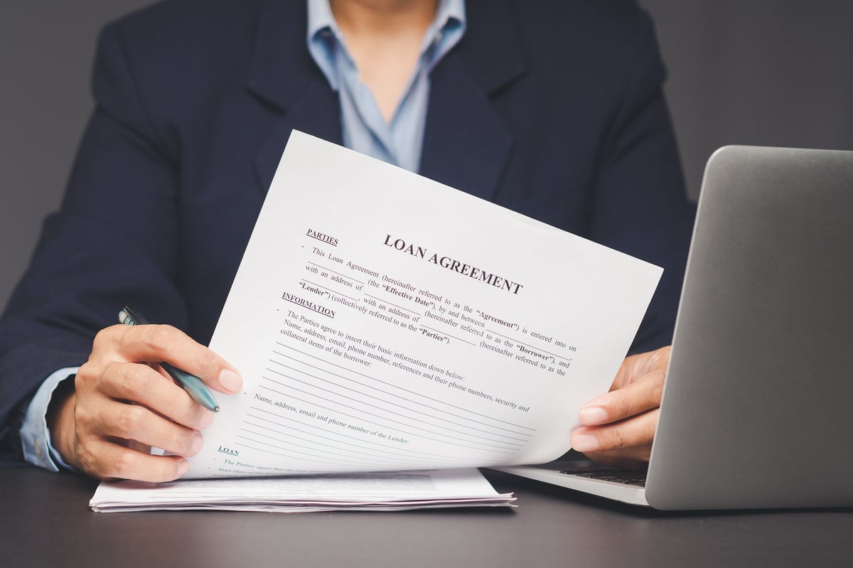 Close-up of businessperson reviewing loan form at office desk. Finance, mortgage, legal agreement, and banking paperwork ideal for credit application or money lending visuals.