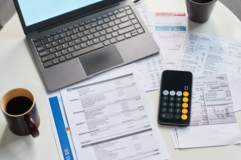 Closeup of financial documents, calculator, and laptop on table illustrating business valuation