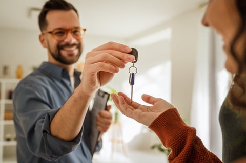 Person receiving a set of house keys from a real estate agent, symbolizing new home ownership, property transfer, and a successful real estate transaction