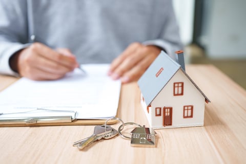 Property agreement signing with house model and keys for real estate purchase, mortgage documentation, lease contract, and ownership transfer.