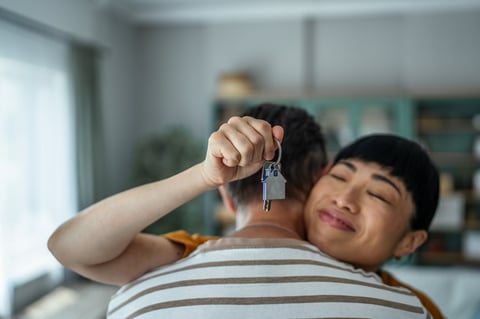 Happy couple holding house keys and celebrating their new home purchase