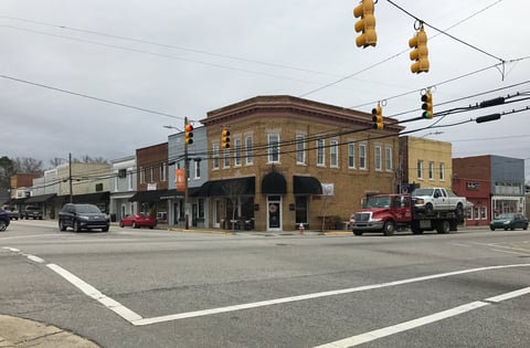 Brick downtown building at street intersection with traffic lights, parked cars and delivery trucks visible