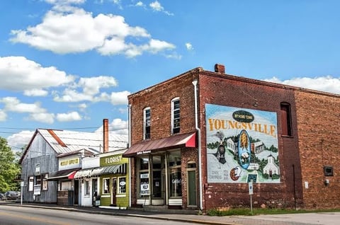 Vintage brick building with Youngs store storefront and painted sign on side wall under blue sky with clouds