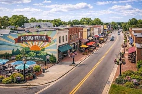 Aerial view of Fuquay-Varina main street with historic brick buildings, colorful mural, and landscaped plaza