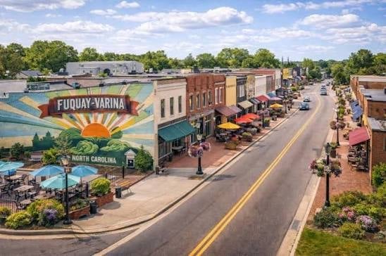 Aerial view of Fuquay-Varina main street with historic brick buildings, colorful mural, and landscaped plaza